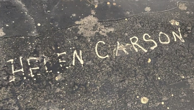 Close-up of “Helen Carson” carved into the platen of the book press.